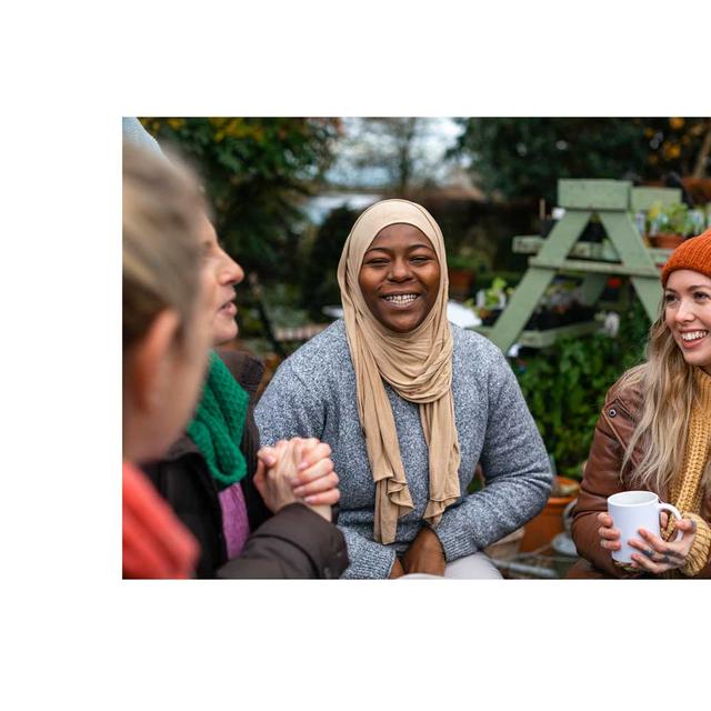 A group of diverse young adults sitting in a circle, laughing.